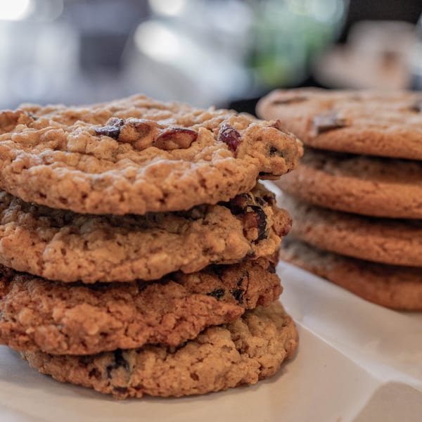 Two stacks of freshly baked oatmeal raisin cookies on a white surface at Tortoni Caffe.
